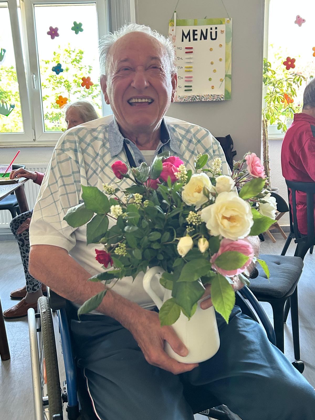 Lachender Bewohner mit Blumenstrauß – Lebensfreude in unseren Wohngemeinschaften